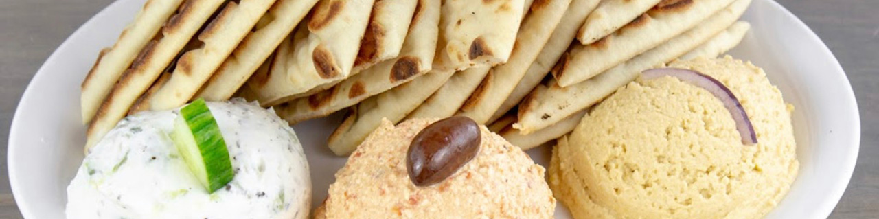 A spread of Greek dishes — gyros, salads, dips and grilled meats