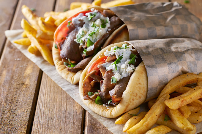 Two fresh gyros wraps stuffed with rotisserie meat, tomato and tzatziki
